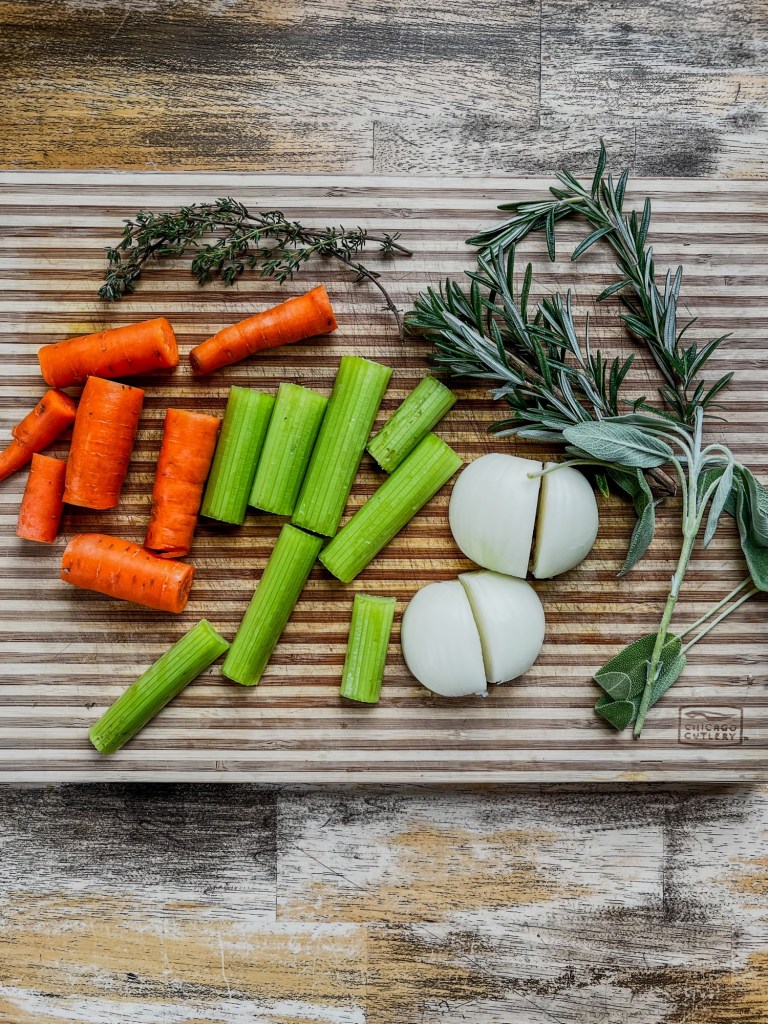 Veggies and herbs on a wooden cutting board on a table