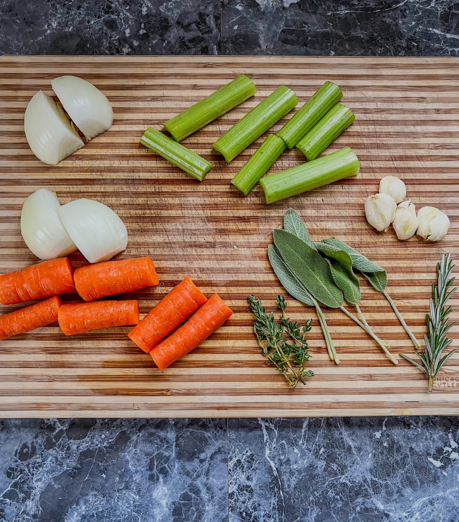 Veggies and herbs on a wooden cutting board, to make a stock