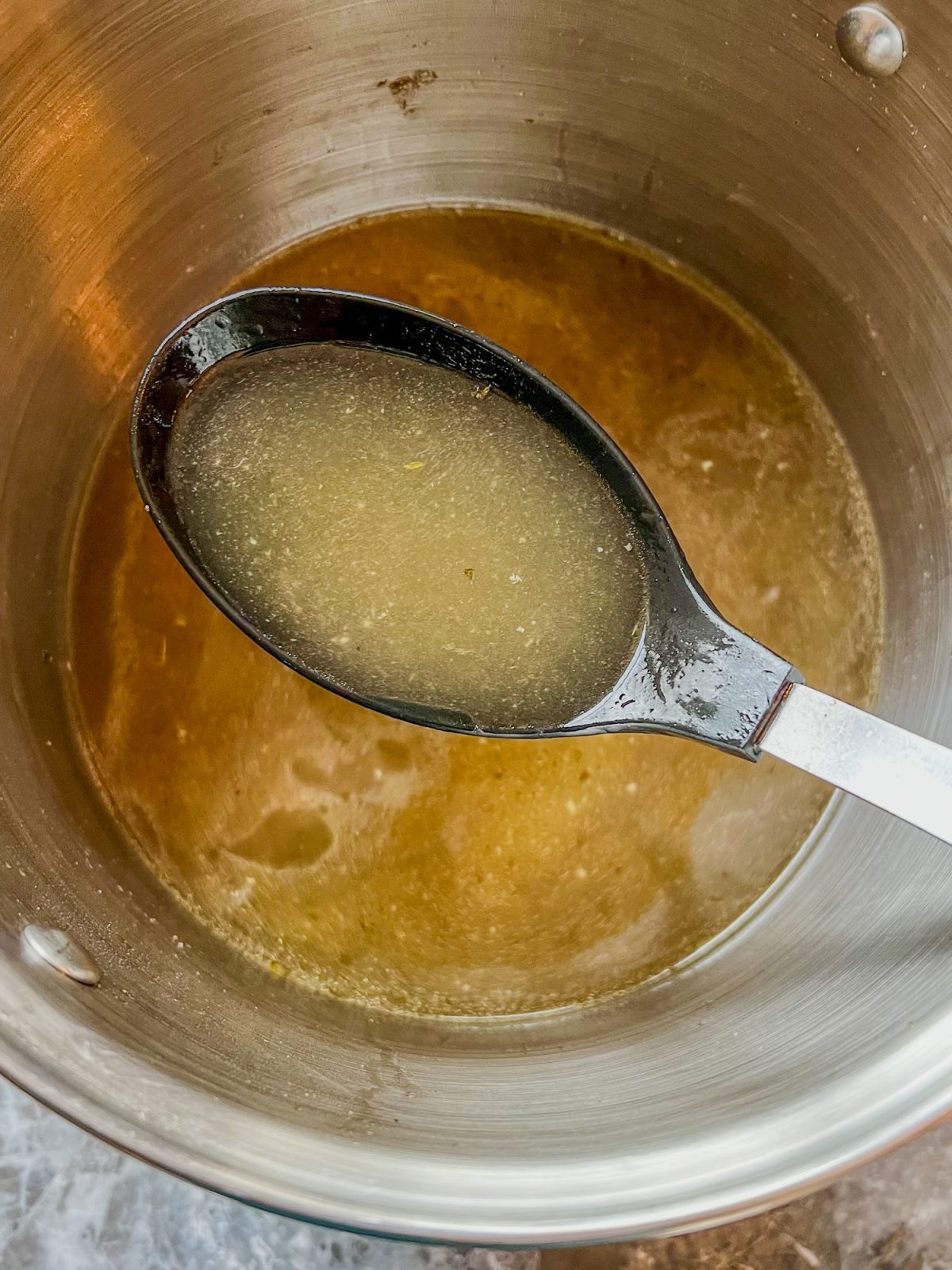 Homemade Turkey Stock in a large pot with a spoon scooping some out