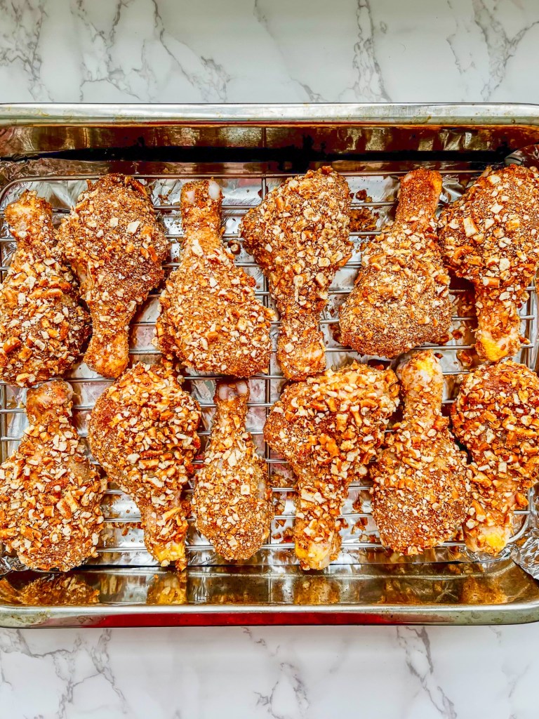 Honey mustard chicken drumsticks with a pretzel coating on top, ready to be baked