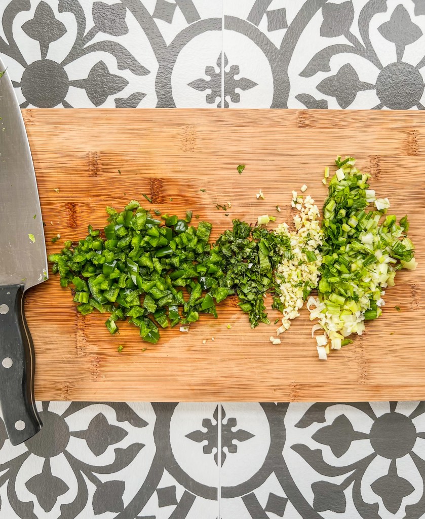 Onion, jalapeño, garlic, and cilantro chopped up on a cutting board
