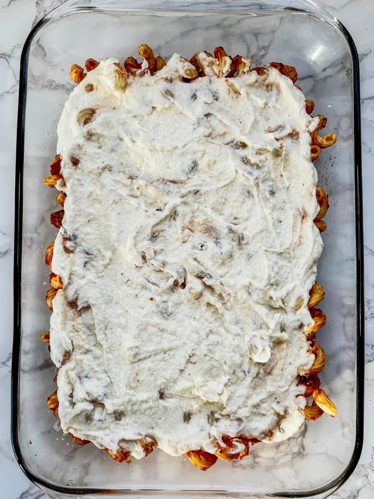 Lasagna style baked ziti being built in a baking pan