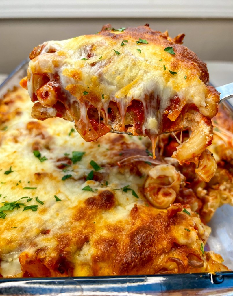 Lasagna ziti bake in a pan with a spoon scooping some out to show the inside