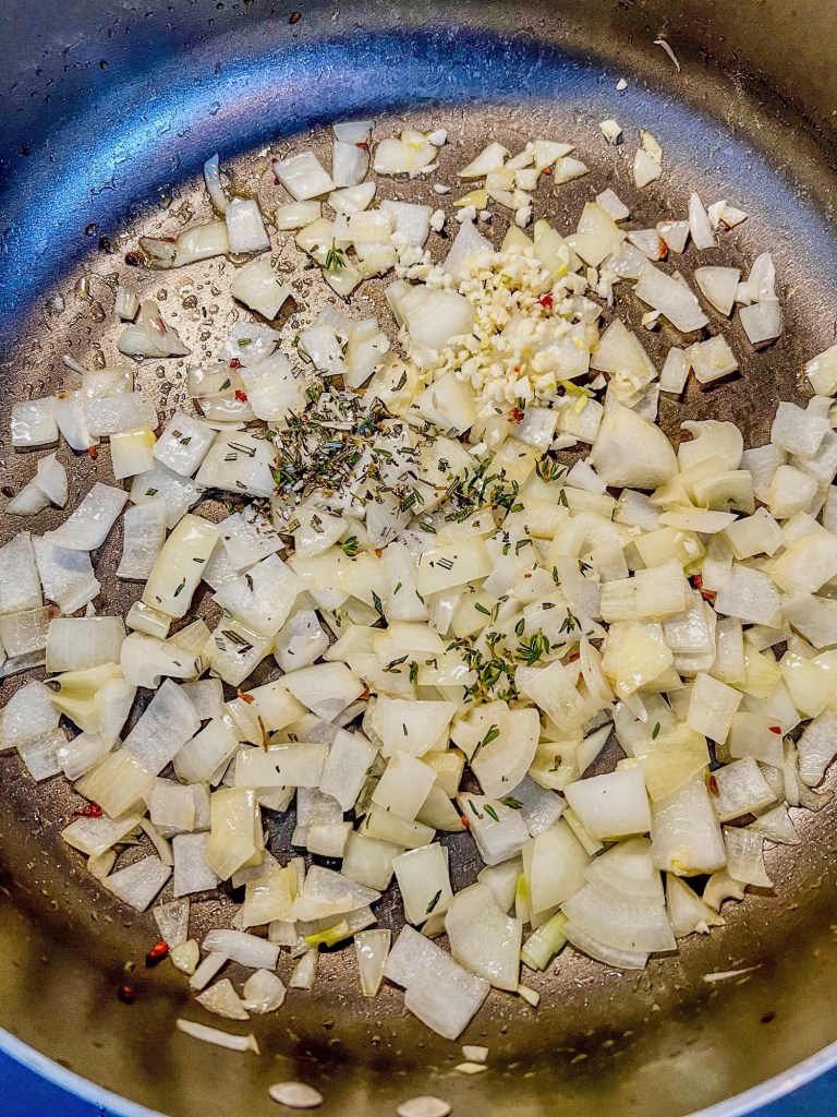 Onion, garlic, butter, and herbs cooking in a skillet