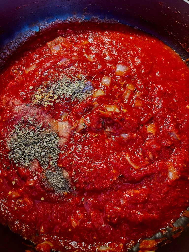 Tomato sauce cooking in a pan with some newly added spices