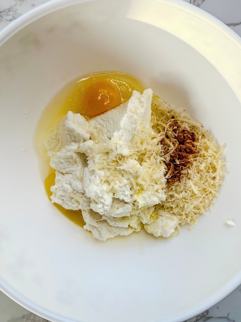 Ingredients for ricotta cheese layer getting added to a bowl