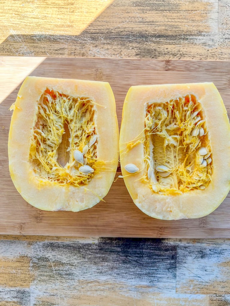 Spaghetti squash that's been cut in half on a wooden cutting board