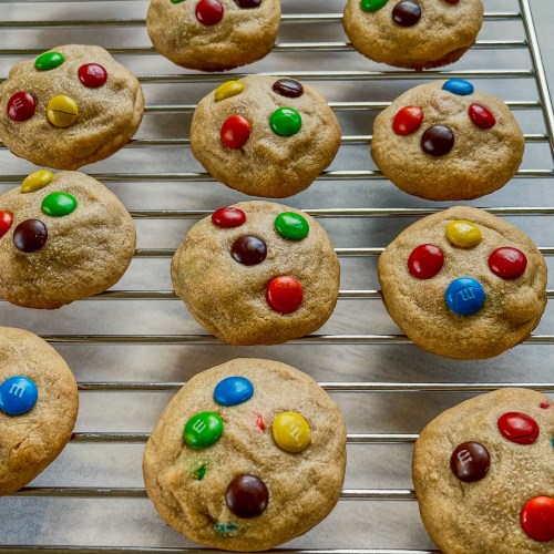 Peanut Butter M&M cookies on a baking rack over some parchment paper
