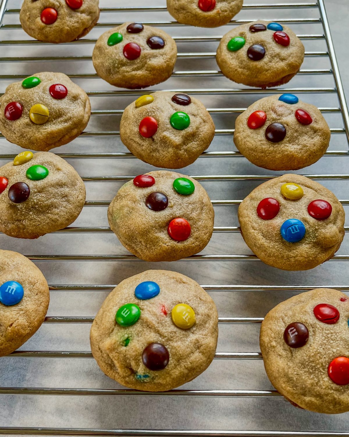 Peanut Butter M&M cookies on a baking rack over some parchment paper