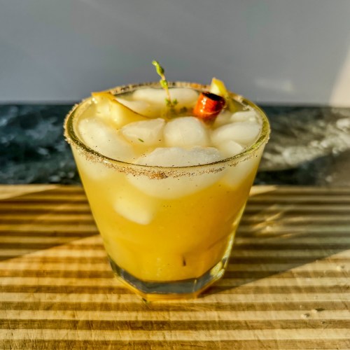 Pear bourbon smash with fresh thyme, pear slices, and a cinnamon stick for garnish