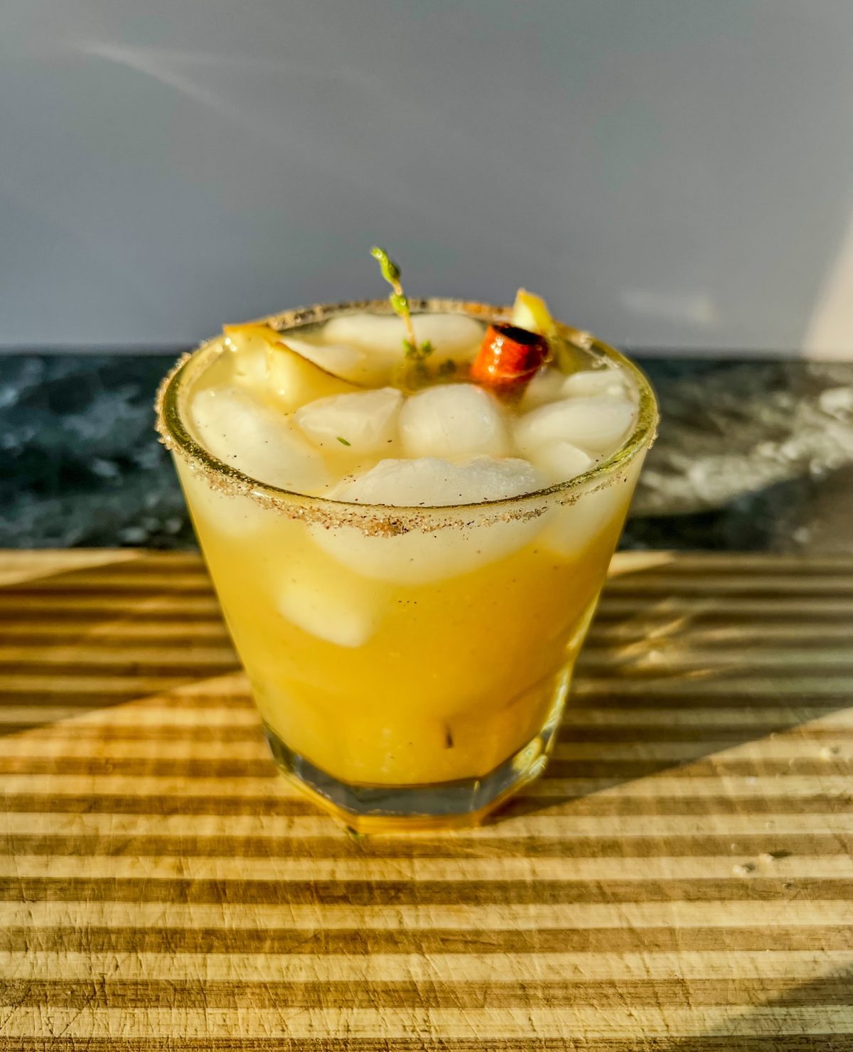 Pear bourbon smash with fresh thyme, pear slices, and a cinnamon stick for garnish