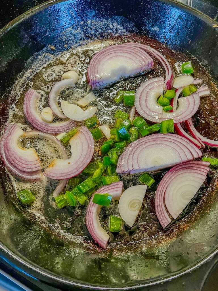 Red onion and jalapeno cooking in a pan on the stove
