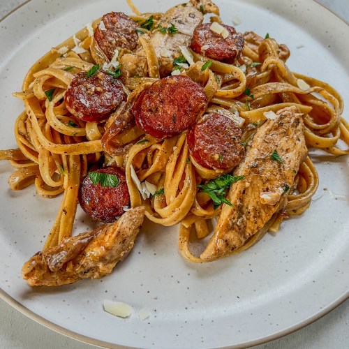 Sausage Chicken Cajun Pasta on a white plate with parsley and parmesan on top