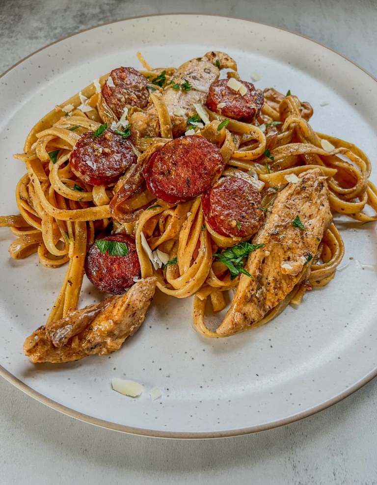 Sausage Chicken Cajun Pasta on a white plate with parsley and parmesan on top