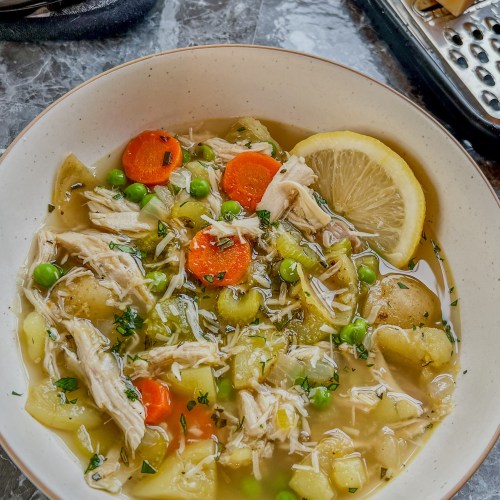 A white bowl filled with turkey stew with a lemon wedge on the side