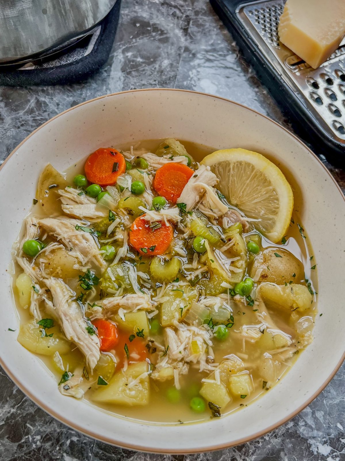 A white bowl filled with turkey stew with a lemon wedge on the side