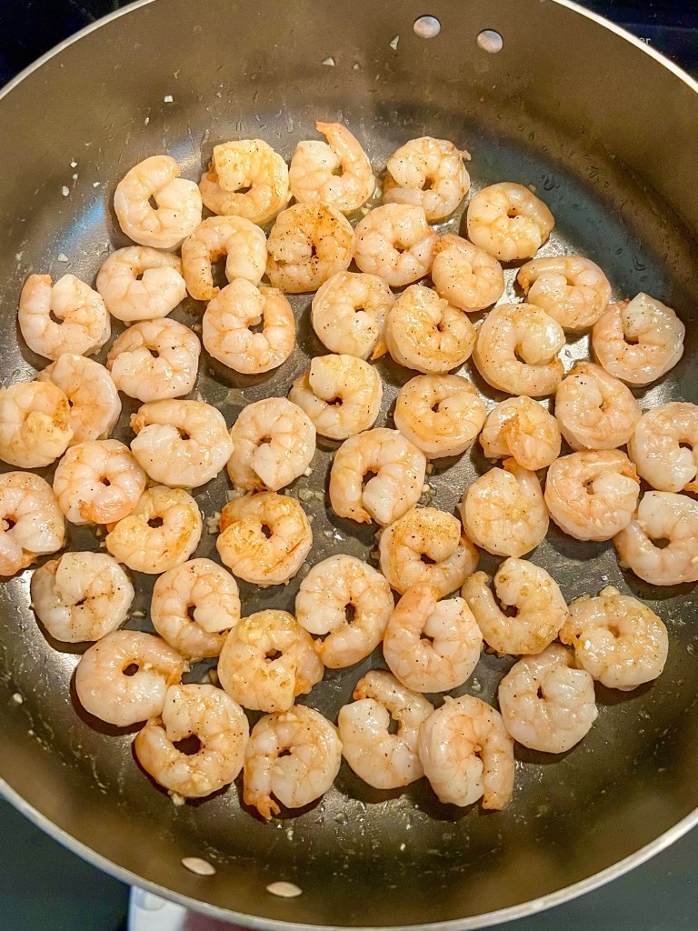 Shrimp cooking in a large skillet on the stove