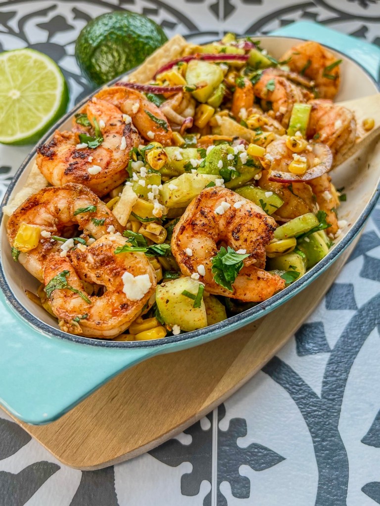 Avocado Shrimp Salad in a dish with a wooden spoon scooping some out and some lime and avocado off to the side