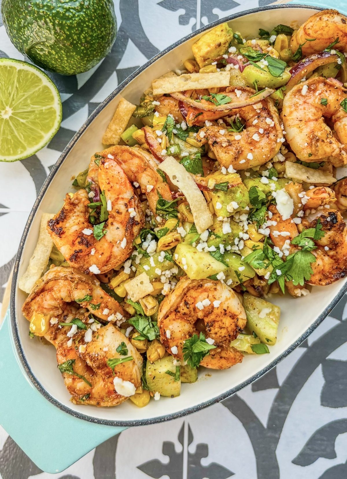 Avocado Shrimp Salad in a dish with a wooden spoon scooping some out and some lime and avocado off to the side