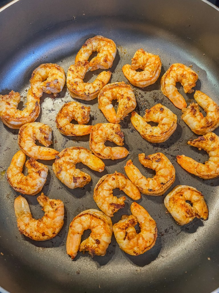 Shrimp cooking in a skillet until pink and slightly charred