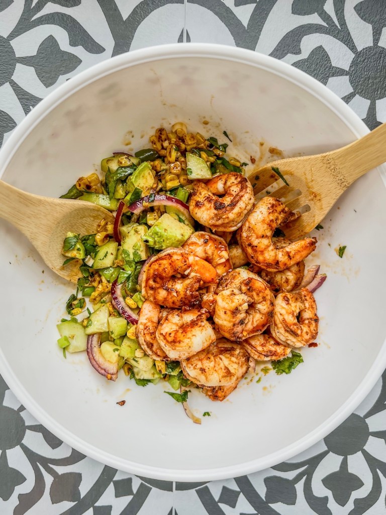 Ingredients for avocado shrimp salad being tossed in a large bowl