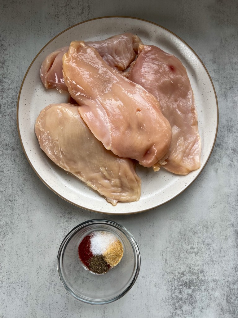 Chicken breasts with pockets cut into them with some spices off to the side