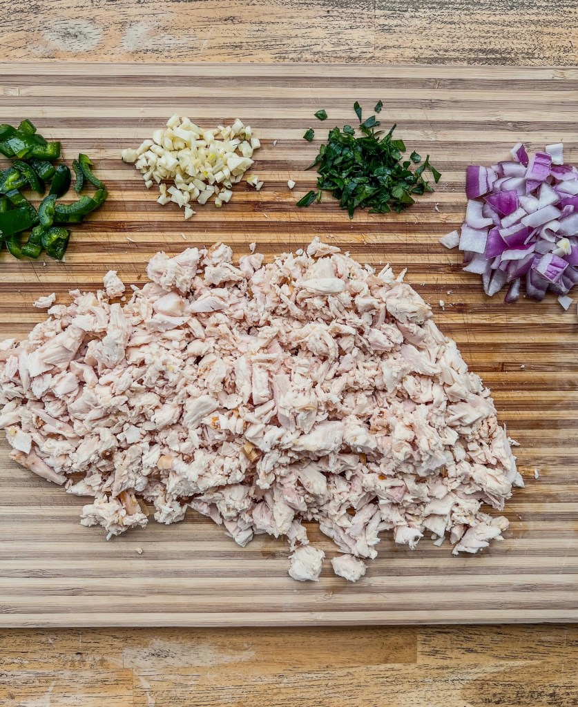 Ingredients for Cajun chicken salad on a wooden cutting board