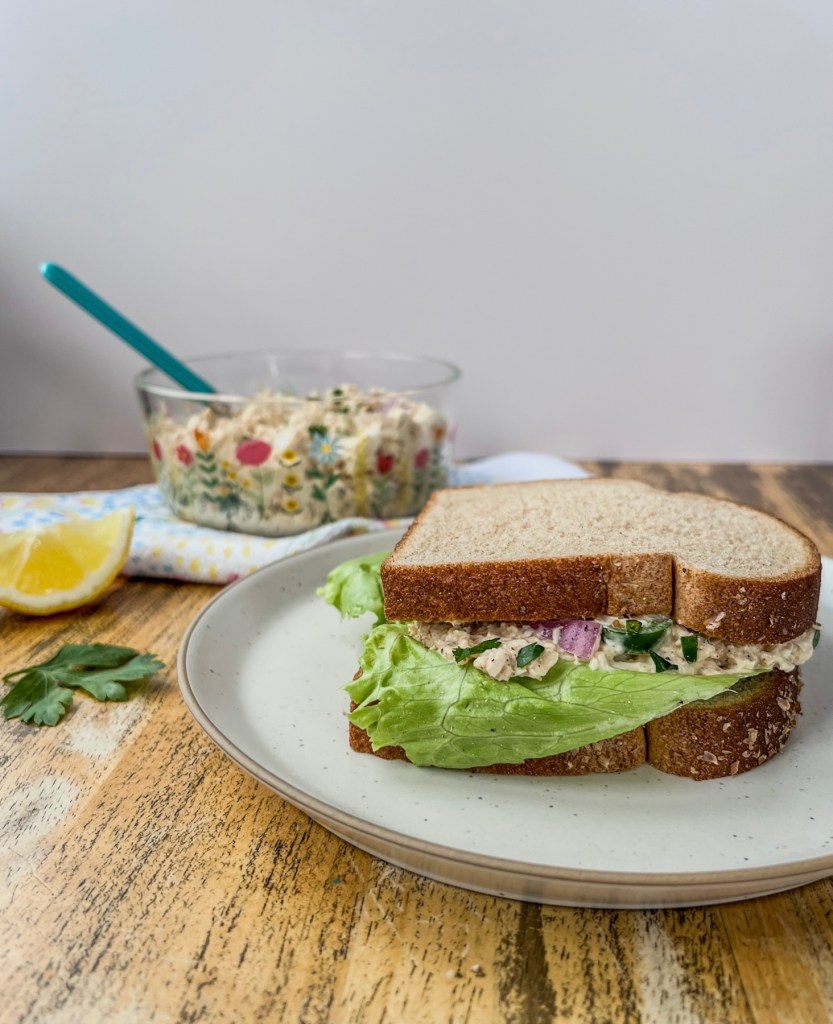 A Cajun chicken salad sandwich with fresh lettuce, with some more chicken salad in a bowl off to the side