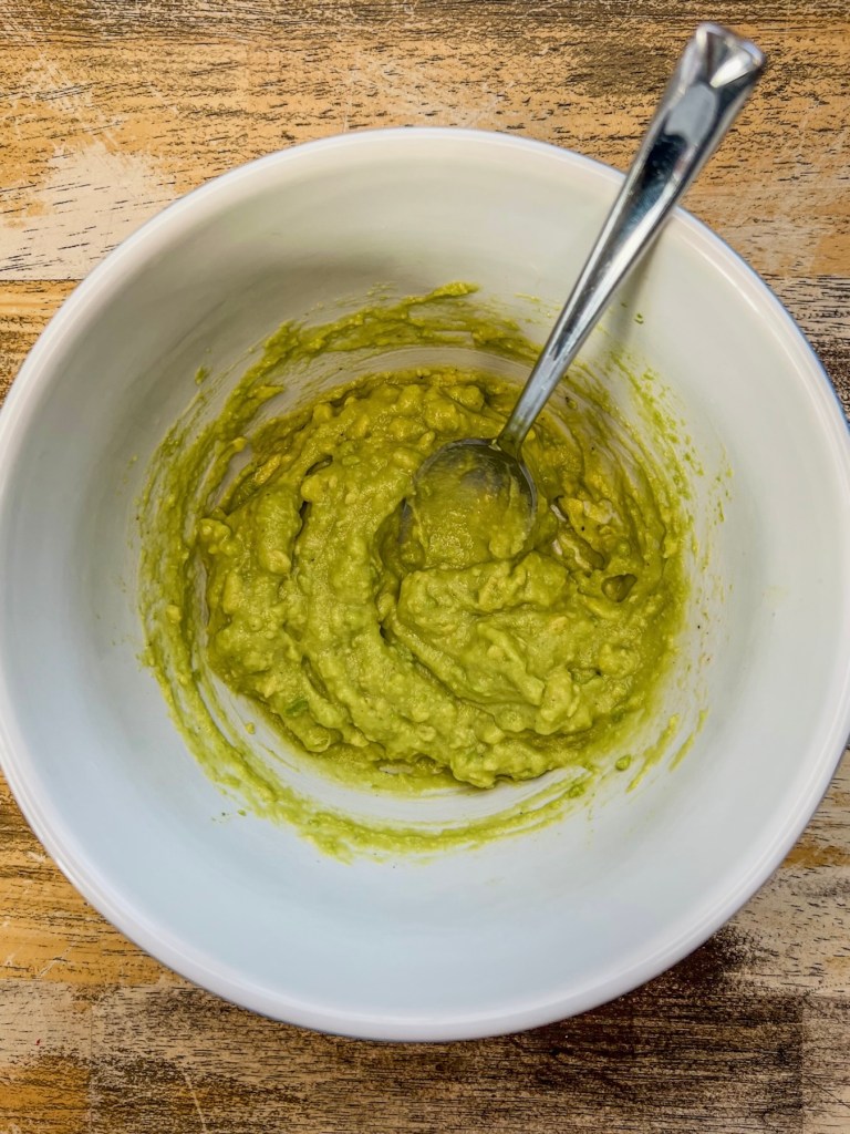 Homemade avocado sauce in a bowl with a spoon inside