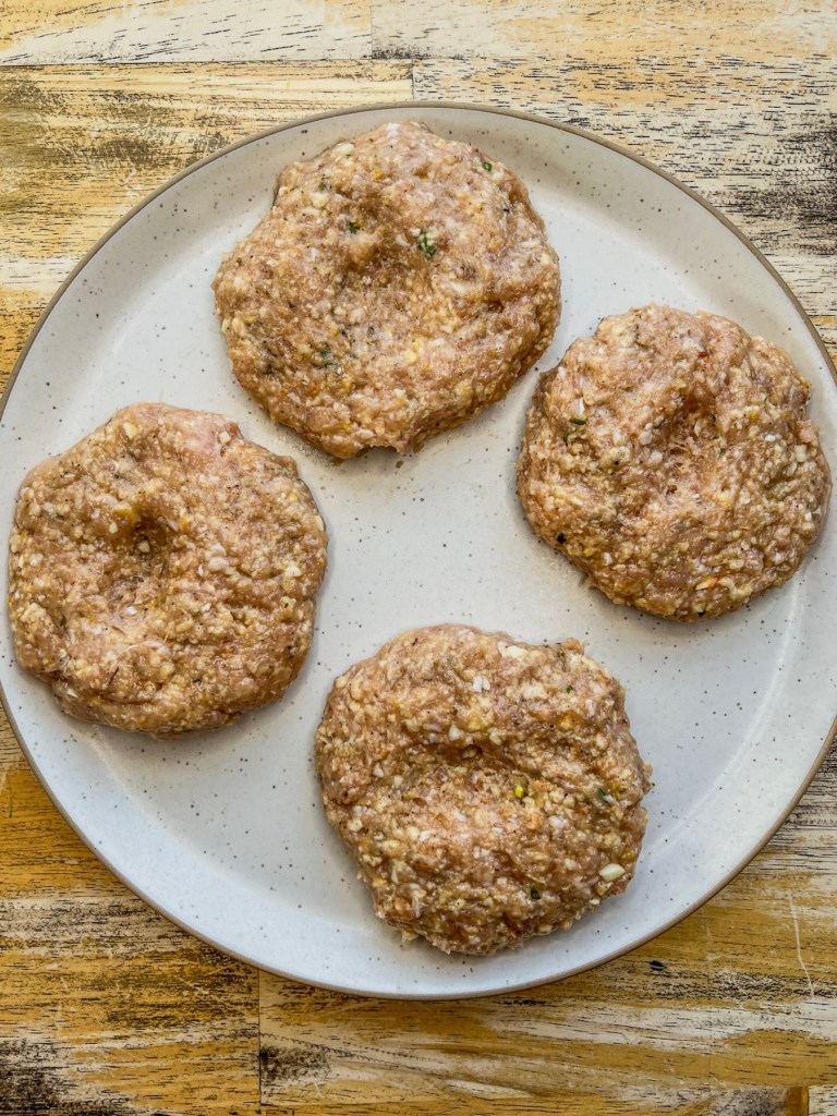 Four raw patties on a plate before going into the fridge