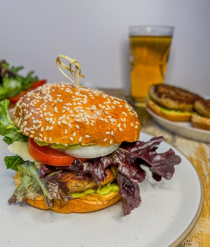 California chicken burger with fresh veggies and avocado sauce with some more burgers and beer off to the side