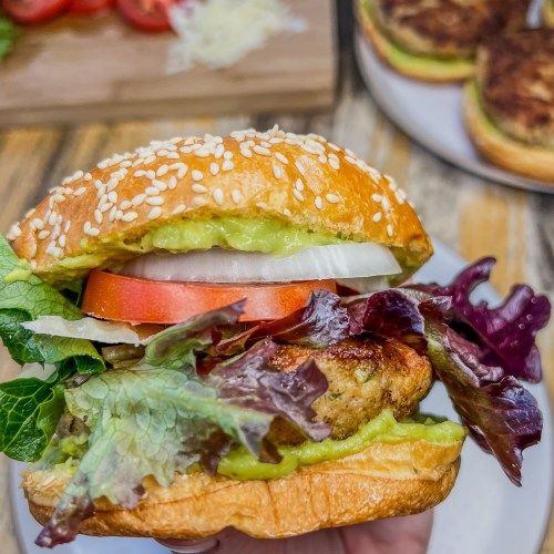 California chicken burger with avocado sauce and fresh veggies piled on with some more ingredients off to the side