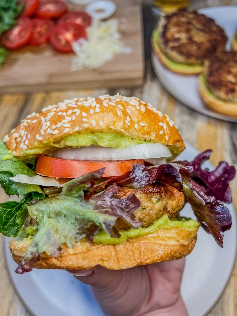 California chicken burger with avocado sauce and fresh veggies piled on with some more ingredients off to the side