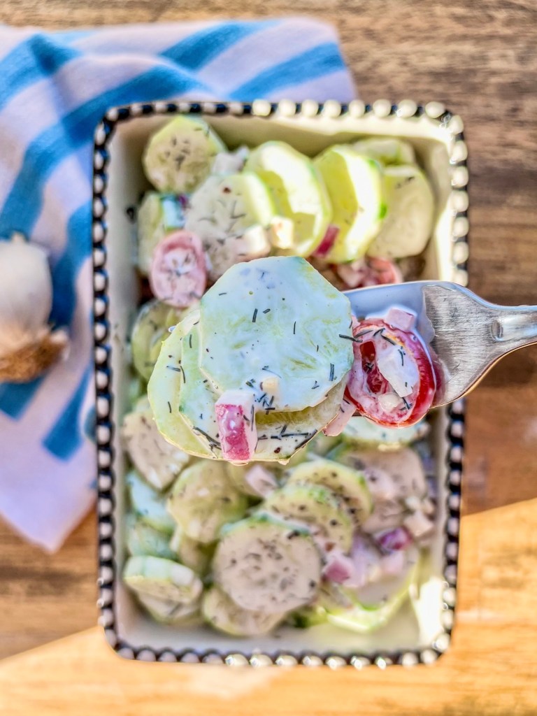 Creamy cucumber salad in a dish with a fork scooping some out