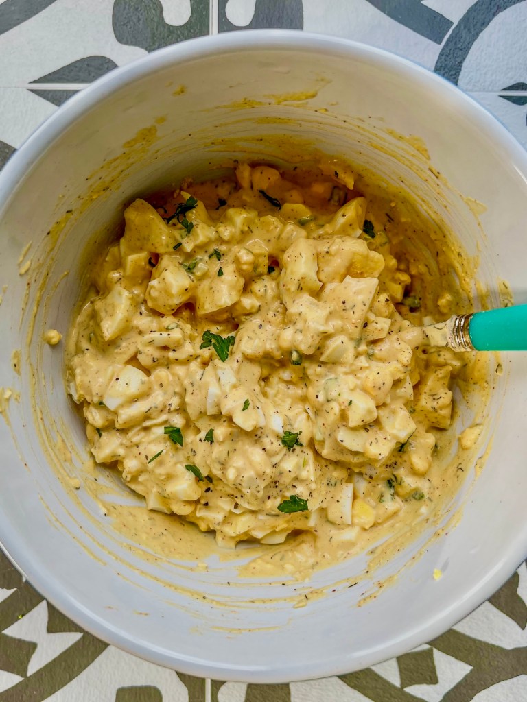 Creamy egg salad in a bowl with freshly cracked black pepper on top