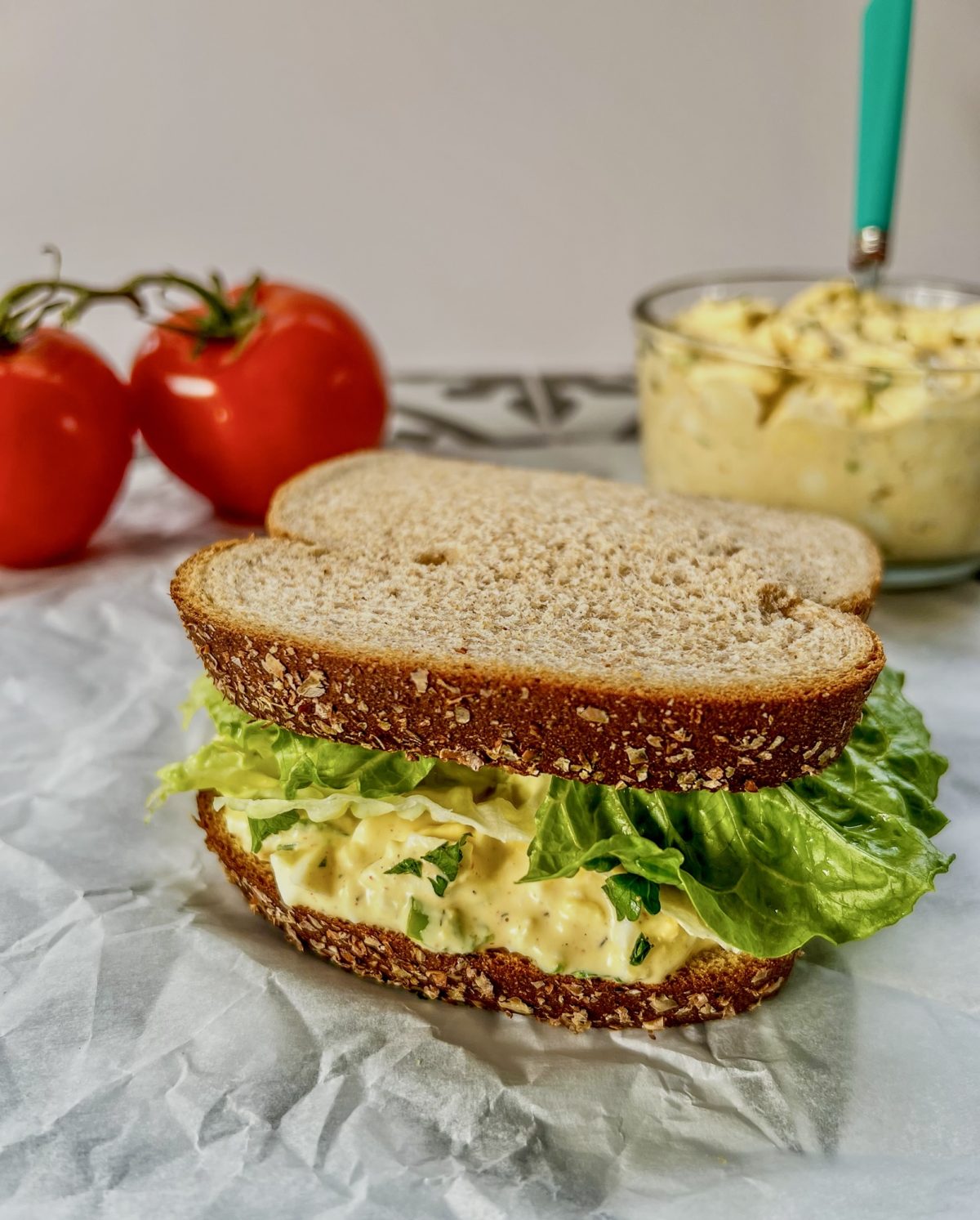 Creamy egg salad smeared on bread with some fresh lettuce to make a sandwich