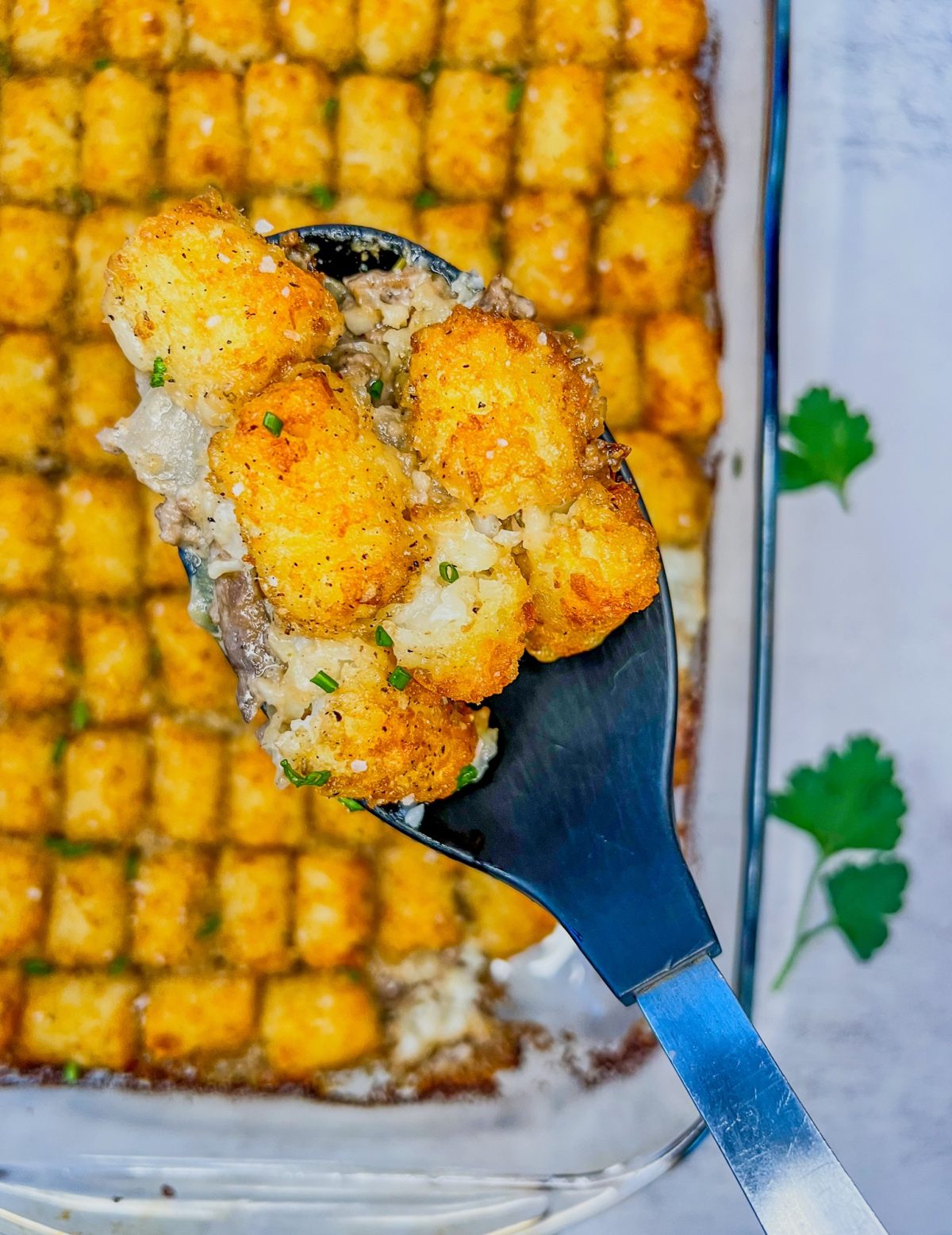 Creamy mushroom tater tot casserole in a baking dish with a spoon scooping some out