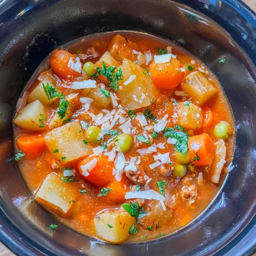 Crockpot Hamburger Stew in a black bowl with fresh parsley and parmesan on top