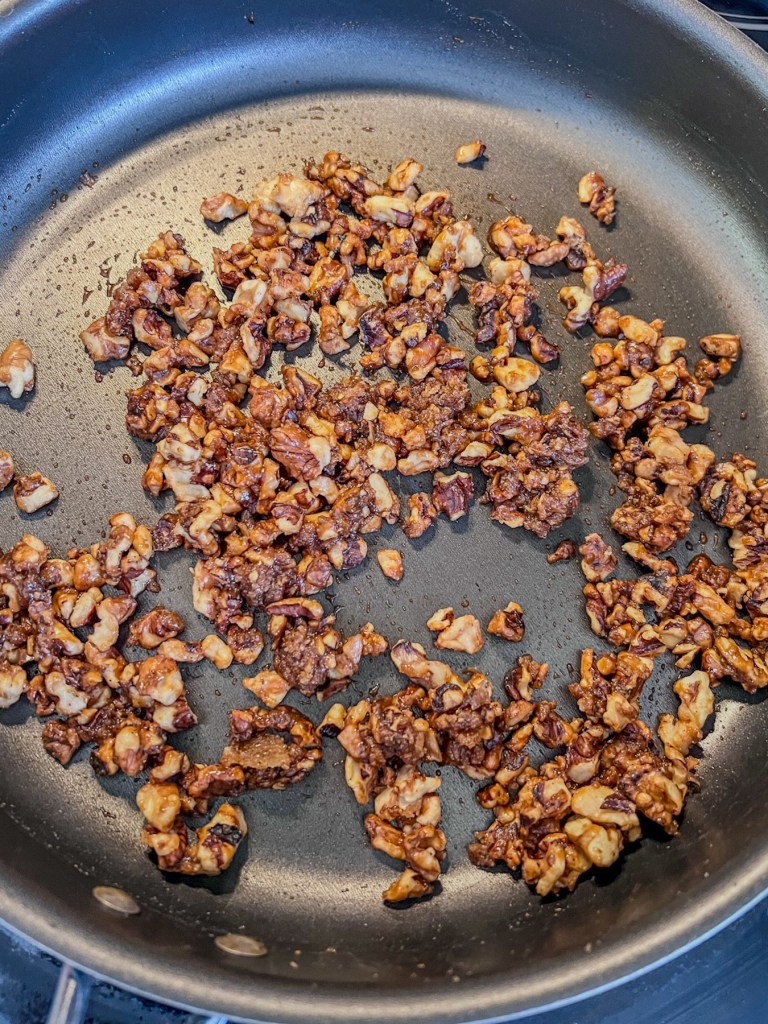 Walnuts, brown sugar, and salt cooking in a skillet to make candied walnuts