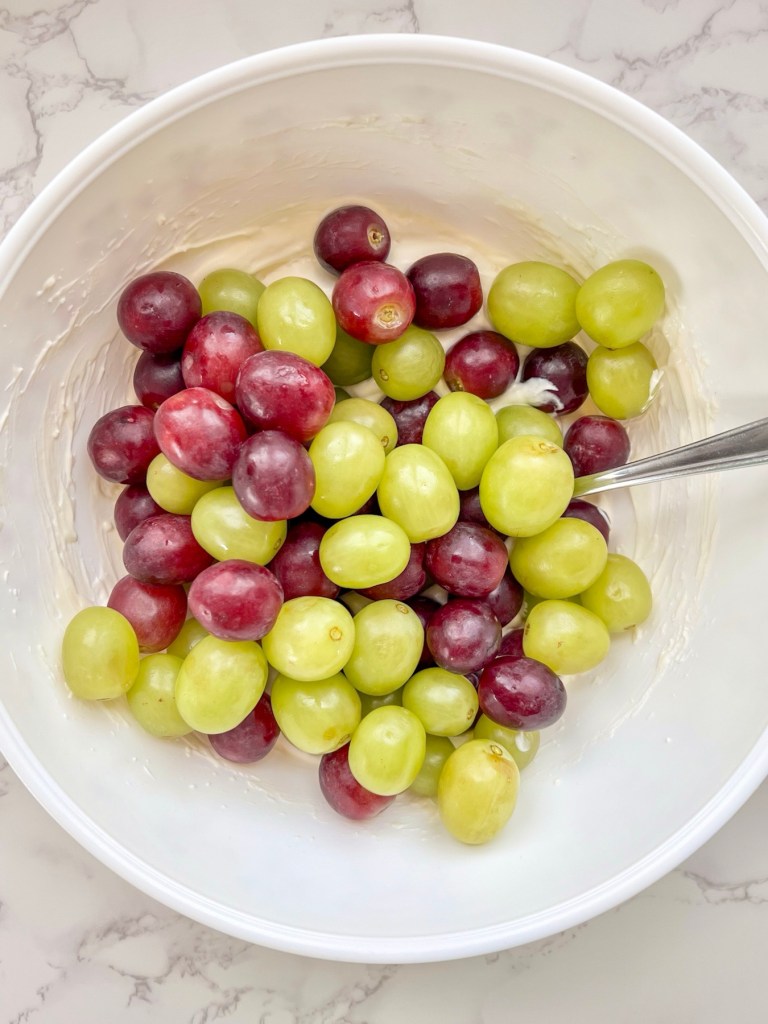 Grapes freshly added to a bowl of filling for grape salad recipe