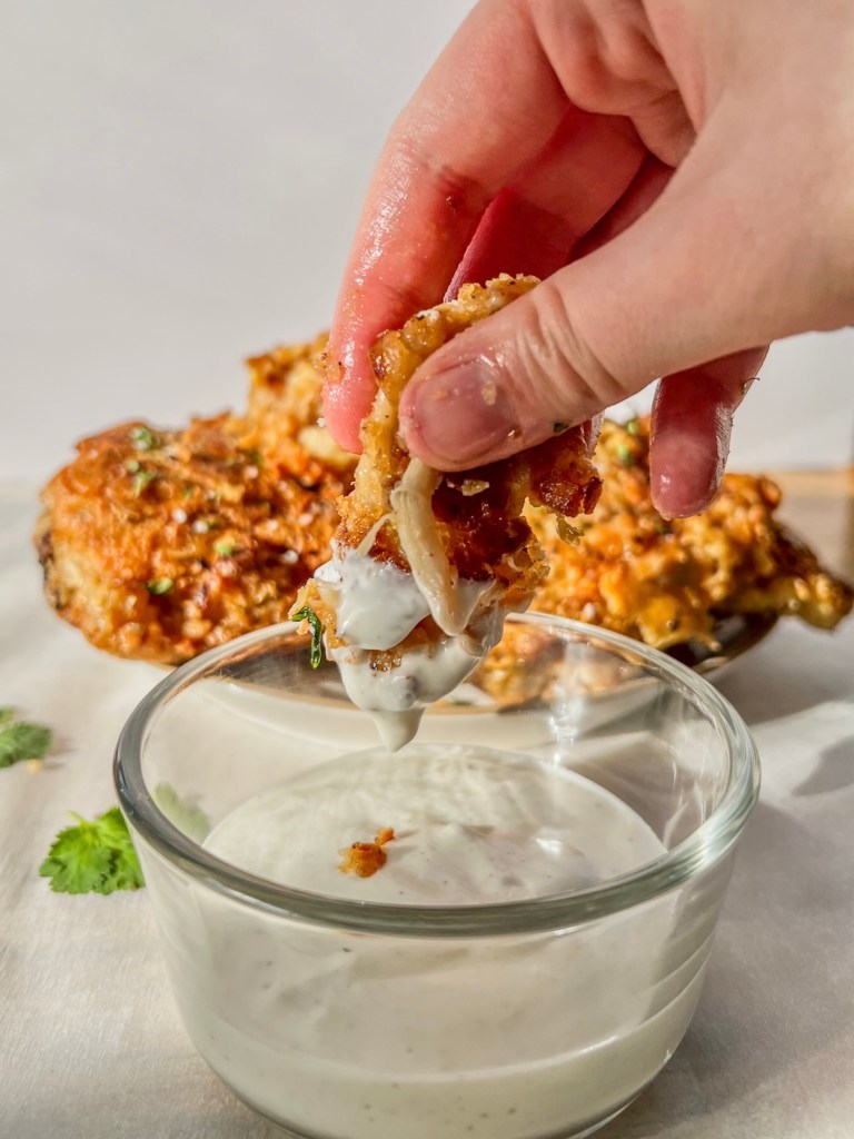 Freshly made hot honey fried chicken thighs being dipped in some ranch sauce