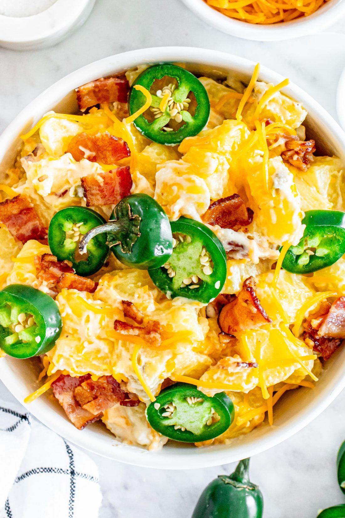 Jalapeño popper potato salad in a dish with some fresh peppers off to the side