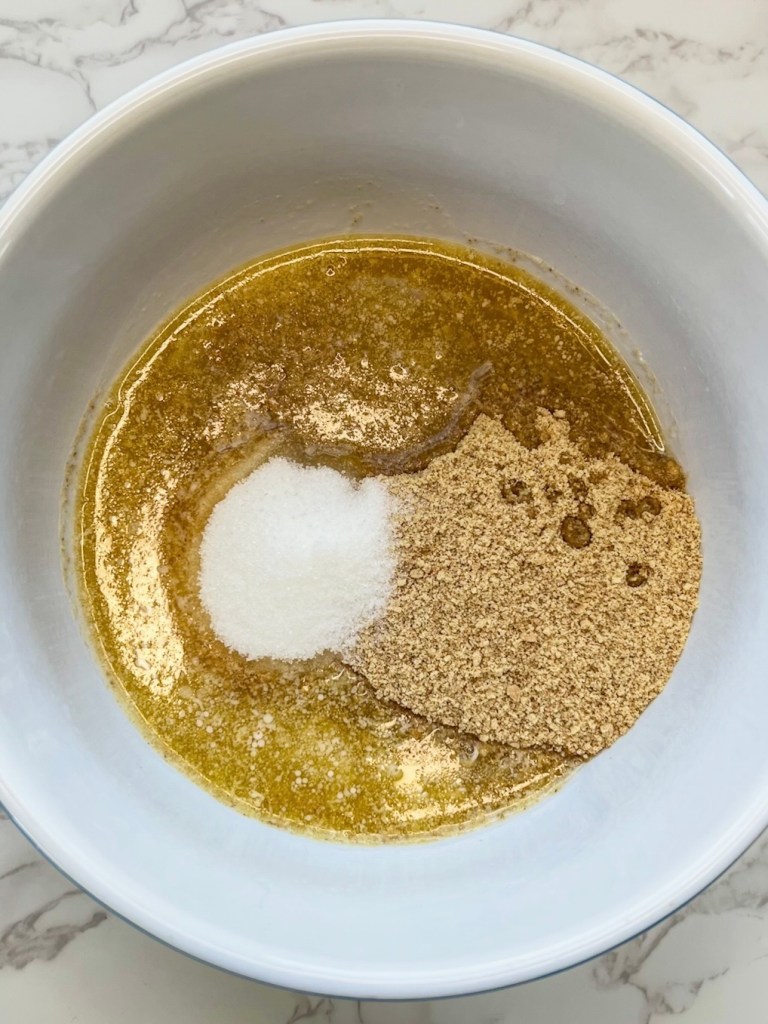 Crushed graham cracker, melted butter, and granulated sugar in a mixing bowl