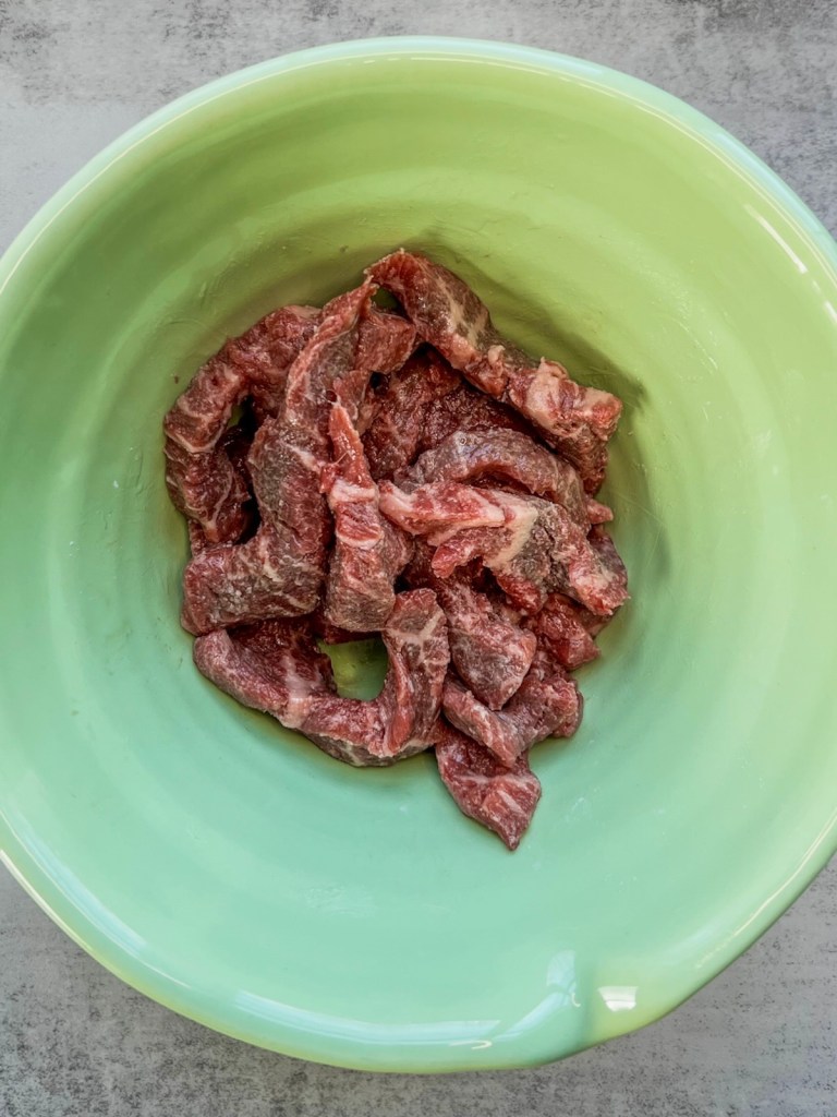 Stir fry beef in a bowl with cornstarch, oil, and spices rubbed on it