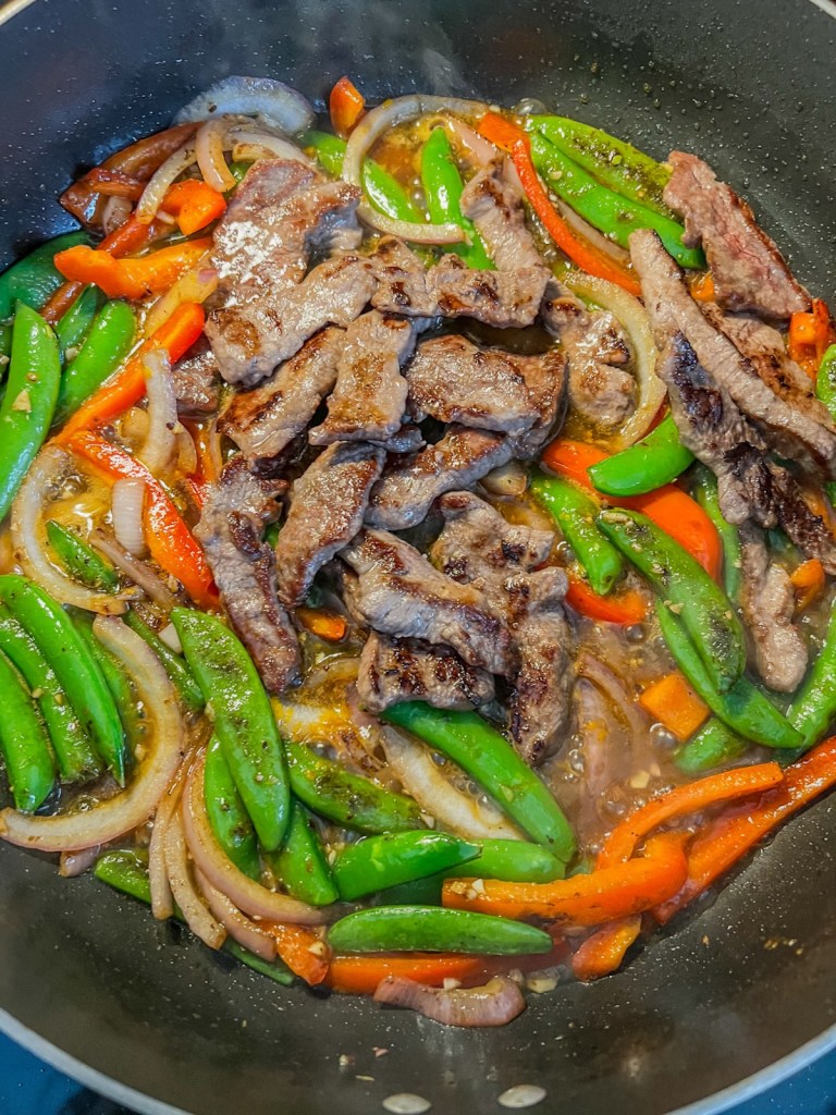 Sticky orange beef stir fry coming together in a large skillet