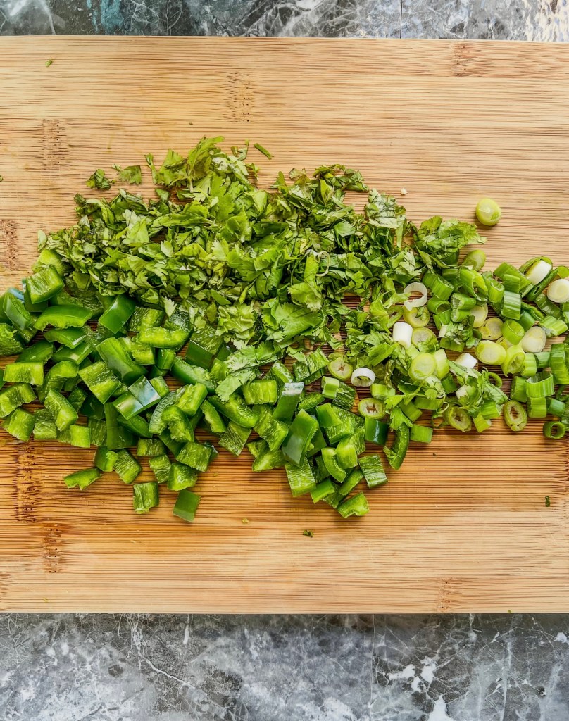 Jalapeños, green onion, and cilantro cut up on a cutting board