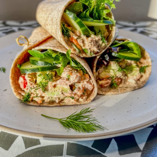 Tuna avocado wraps stacked up on a plate with some fresh dill sprinkled on top