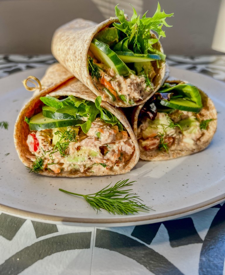 Tuna avocado wraps stacked up on a plate with some fresh dill sprinkled on top