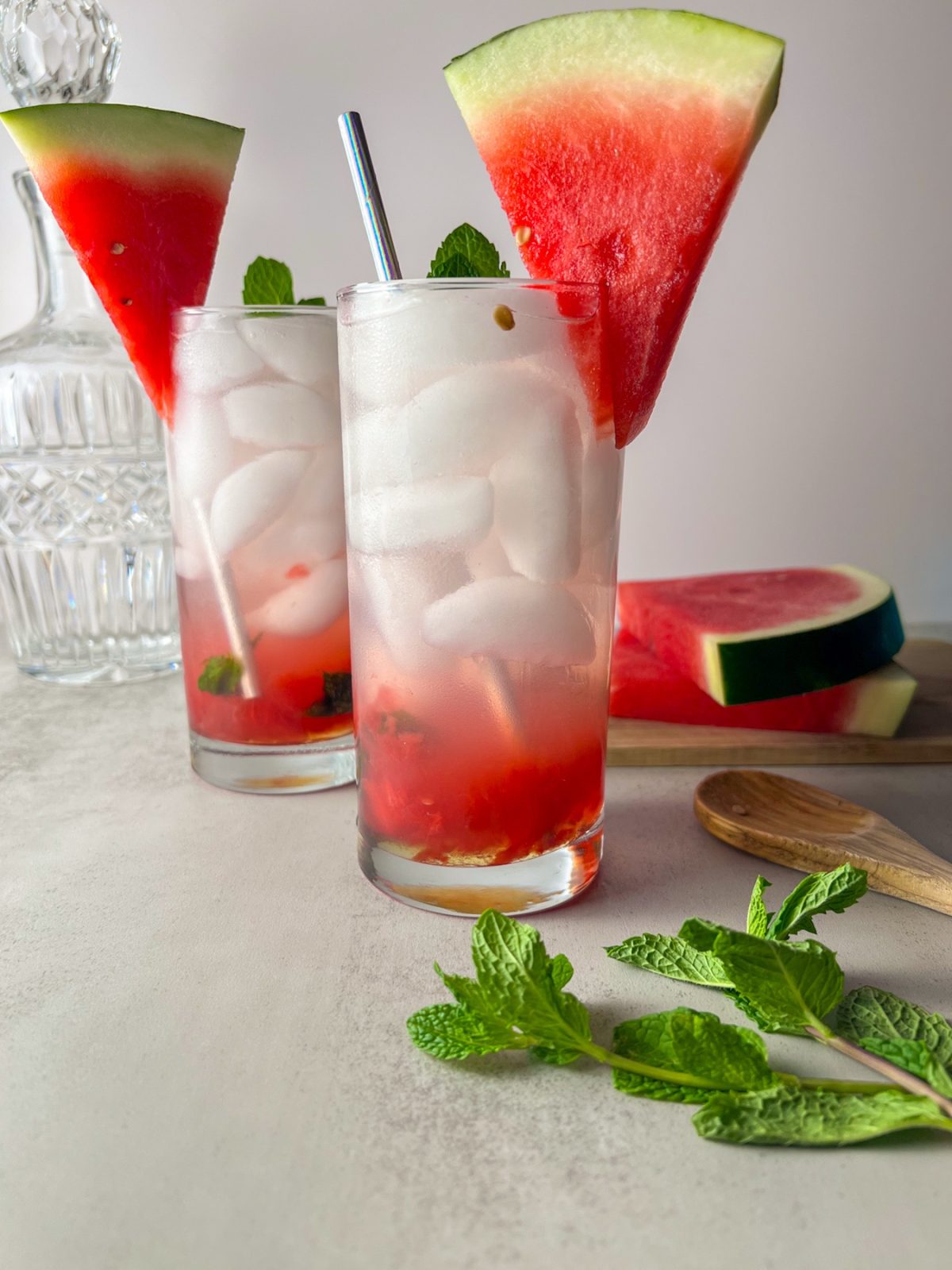 Two watermelon mojito cocktails with mint and watermelon slices garnished on top