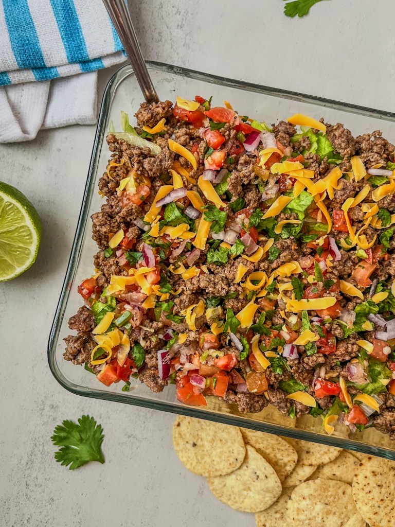 Beefy ranch taco dip made with cottage cheese and Greek yogurt served with fresh veggies, cheese, and tortilla chips
